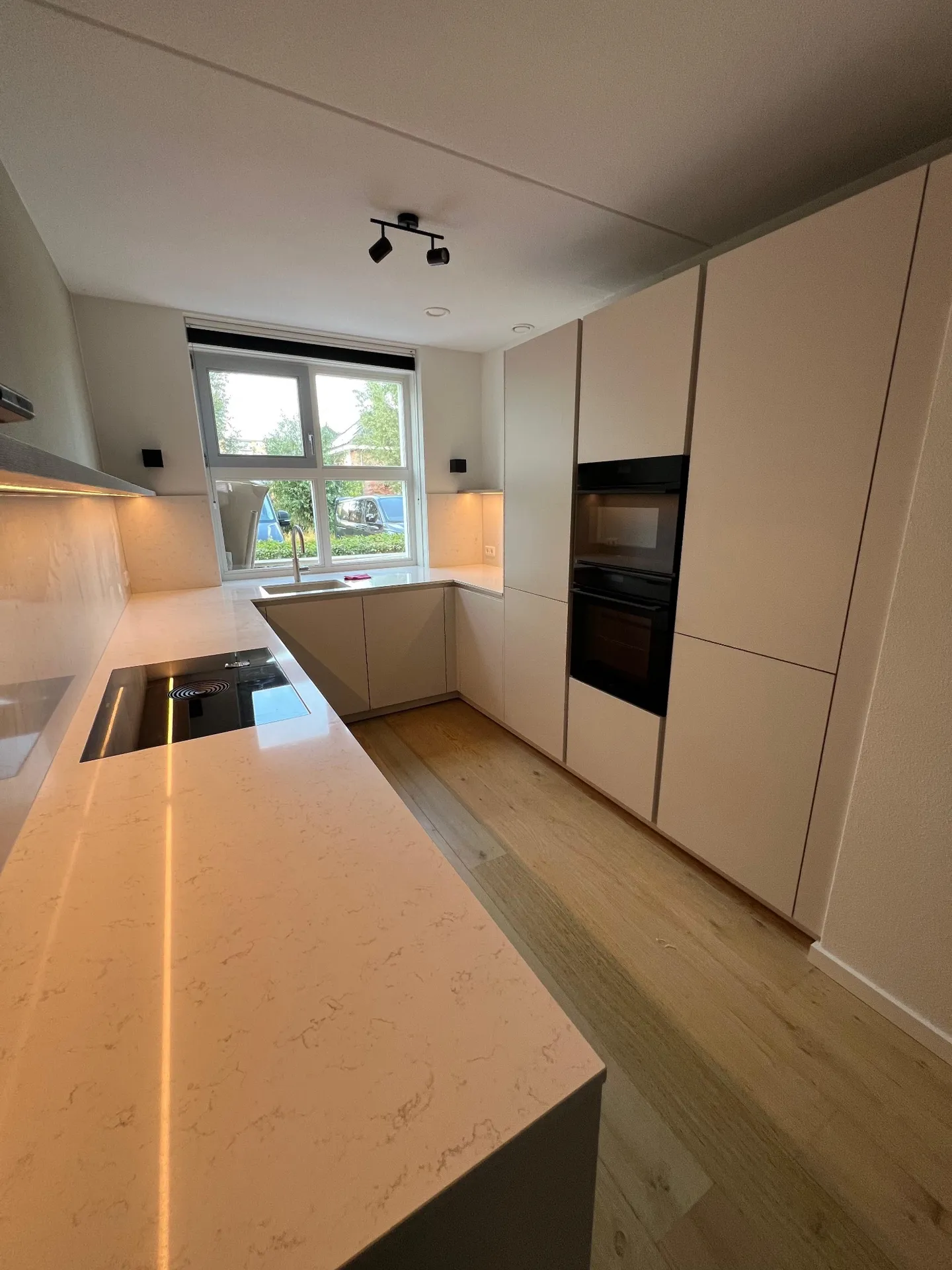 Lichte hoekkeuken met hoge kastenwand, werkblad en spoelgedeelte