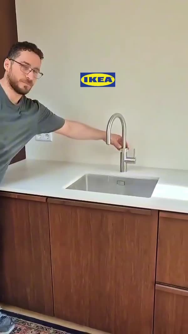 Spoelbak met kraan in een wit werkblad, met donkere houten fronten eronder