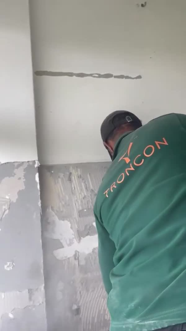 Monteur van Troncon werkt aan de kale keukenwand